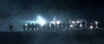 Movie still from “Alien vs. Predator” (2004), directed by Paul W.S. Anderson – A group of people standing in the dark with headlights on; Extreme Wide shot, Low angle