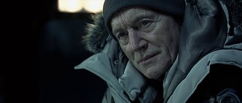 Movie still from “Alien vs. Predator” (2004), directed by Paul W.S. Anderson – An older man wearing a winter coat and a hat; Close Up shot, Over the shoulder angle
