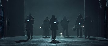 Movie still from “Alien vs. Predator” (2004), directed by Paul W.S. Anderson – A group of people standing in the dark with their lights on; Wide shot, Low angle