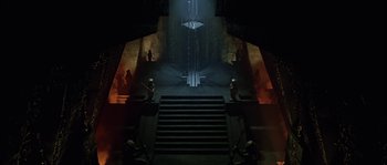 Movie still from “Alien vs. Predator” (2004), directed by Paul W.S. Anderson – A staircase leading up to a dark room with statues; Extreme Wide shot, High angle