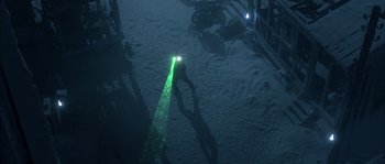 Movie still from “Alien vs. Predator” (2004), directed by Paul W.S. Anderson – A person is standing in the snow holding a flashlight; Extreme Wide shot, Overhead angle