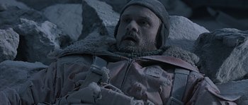 Movie still from “Alien vs. Predator” (2004), directed by Paul W.S. Anderson – A man laying on a bed in the snow; Medium shot, Overhead angle