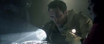 Movie still from “Alien vs. Predator” (2004), directed by Paul W.S. Anderson – A man is holding a flashlight in the dark; Close Up shot, Low angle
