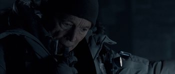 Movie still from “Alien vs. Predator” (2004), directed by Paul W.S. Anderson – An older man wearing a black hat and a black jacket; Close Up shot, Over the shoulder angle
