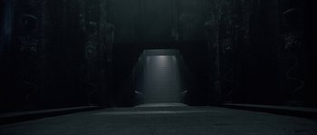Movie still from “Alien vs. Predator” (2004), directed by Paul W.S. Anderson – An empty dark room with stairs leading to the top of the building; Extreme Wide shot, High angle