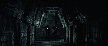 Movie still from “Alien vs. Predator” (2004), directed by Paul W.S. Anderson – Two people are standing in a dark tunnel; Wide shot, Low angle