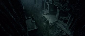 Movie still from “Alien vs. Predator” (2004), directed by Paul W.S. Anderson – A person standing in a room with a lot of dirt on the ground; Extreme Wide shot, Overhead angle