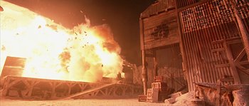 Movie still from “Alien vs. Predator” (2004), directed by Paul W.S. Anderson – An explosion is seen in the background of a building; Extreme Wide shot, Low angle
