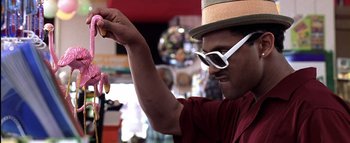 Movie still from “All About the Benjamins” (2002), directed by Kevin Bray – A man holding a piece of food while wearing sunglasses; Close Up shot, Low angle
