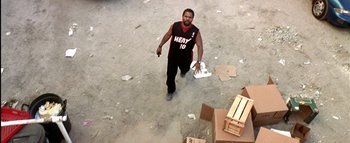 Movie still from “All About the Benjamins” (2002), directed by Kevin Bray – A man walking across a cement floor holding a gun; Wide shot, High angle