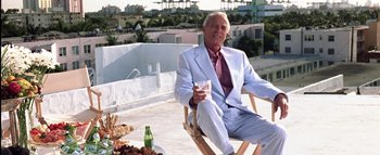Movie still from “All About the Benjamins” (2002), directed by Kevin Bray – An older man in a white suit sitting on a chair; Wide shot, Low angle