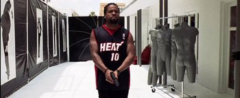 Movie still from “All About the Benjamins” (2002), directed by Kevin Bray – A man holding a gun while standing in front of mannequins; Medium shot, Low angle