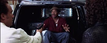 Movie still from “All About the Benjamins” (2002), directed by Kevin Bray – A man sitting in the back of a car talking to a man holding a gun; Medium shot, Over the shoulder angle