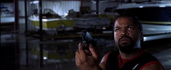 Movie still from “All About the Benjamins” (2002), directed by Kevin Bray – A man holding a gun while standing in a warehouse; Close Up shot, Low angle