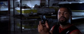 Movie still from “All About the Benjamins” (2002), directed by Kevin Bray – A man holding a gun while standing in a warehouse; Close Up shot, High angle