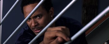 Movie still from “All About the Benjamins” (2002), directed by Kevin Bray – A person behind a metal fence; Close Up shot, High angle