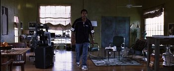 Movie still from “All About the Benjamins” (2002), directed by Kevin Bray – A man walking in a room with a rug on the floor; Wide shot, High angle