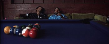 Movie still from “All About the Benjamins” (2002), directed by Kevin Bray – Two men sitting on a couch in front of a table; Medium shot, Low angle