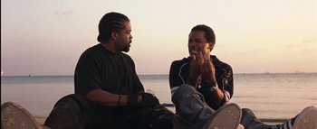 Movie still from “All About the Benjamins” (2002), directed by Kevin Bray – Two men sitting next to each other on the beach; Medium shot, Low angle
