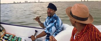 Movie still from “All About the Benjamins” (2002), directed by Kevin Bray – A man holding a cigar while sitting in a boat; Medium shot, High angle