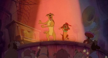 Movie still from “All Dogs Go to Heaven” (1989), directed by Dan Kuenster – A dog and a hound dog are in front of a group of people; Wide shot, Low angle