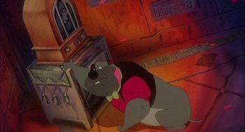 Movie still from “All Dogs Go to Heaven” (1989), directed by Dan Kuenster – A dog sitting on the floor in a room; Medium shot, Low angle