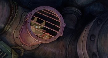 Movie still from “All Dogs Go to Heaven” (1989), directed by Dan Kuenster – A cat is sitting in a cage in a building; Close Up shot, High angle