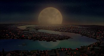 Movie still from “All Dogs Go to Heaven” (1989), directed by Dan Kuenster – An aerial view of a city at night with a full moon in the background; Extreme Wide shot, High angle