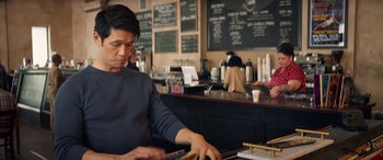Movie still from “All My Life” (2020), directed by Marc Meyers – A man working at a counter in front of a chalkboard; Medium shot, Over the shoulder angle
