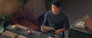 Movie still from “All My Life” (2020), directed by Marc Meyers – A man sitting at a table reading a magazine; Medium shot, Over the shoulder angle