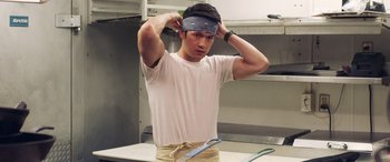 Movie still from “All My Life” (2020), directed by Marc Meyers – A man in a kitchen putting on a headband; Medium shot, Low angle