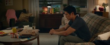 Movie still from “All My Life” (2020), directed by Marc Meyers – A man sitting on a couch in front of a table; Medium shot, Over the shoulder angle