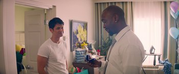 Movie still from “All My Life” (2020), directed by Marc Meyers – Two men in a room with a gift; Medium shot, Over the shoulder angle