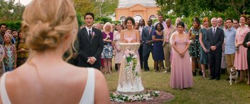 Movie still from “All My Life” (2020), directed by Marc Meyers – A group of people standing in a field with a bride and groom; Wide shot, Over the shoulder angle