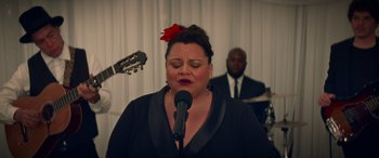Movie still from “All My Life” (2020), directed by Marc Meyers – A woman singing into a microphone in front of a band; Close Up shot, Over the shoulder angle