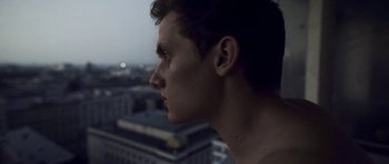 A young man looking out of a window at a city