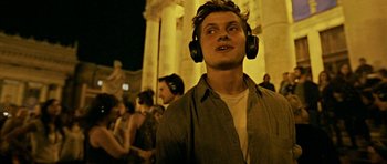 A young man wearing headphones while standing in front of a group of people