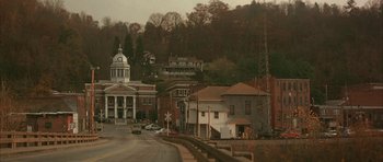 Movie still from “All the Real Girls” (2003), directed by David Gordon Green – A view of a city street with many buildings on the side of the road; Extreme Wide shot, High angle