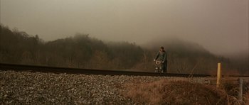 Movie still from “All the Real Girls” (2003), directed by David Gordon Green – A man riding a bike on top of train tracks; Extreme Wide shot, High angle