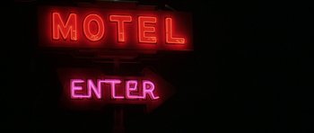 Movie still from “All the Real Girls” (2003), directed by David Gordon Green – A neon sign that reads " hotel " and " center "; Wide shot, High angle