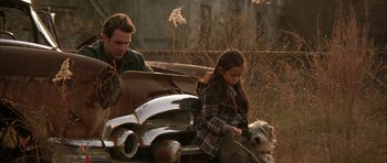 Movie still from “All the Real Girls” (2003), directed by David Gordon Green – A man and a little girl sitting on the back of a car with a dog; Medium shot, Low angle