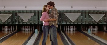 Movie still from “All the Real Girls” (2003), directed by David Gordon Green – A man and a woman kissing in front of a bowling alley; Medium shot, Low angle