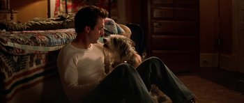 Movie still from “All the Real Girls” (2003), directed by David Gordon Green – A man sitting on a couch with a dog; Medium shot, High angle