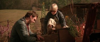 Movie still from “All the Real Girls” (2003), directed by David Gordon Green – A man and a woman sitting on the ground near some plants; Medium shot, Low angle