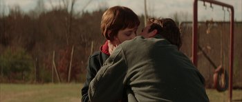 Movie still from “All the Real Girls” (2003), directed by David Gordon Green – A man and a woman kissing in a wooded area; Medium shot, Low angle