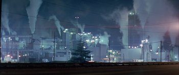 Movie still from “All the Real Girls” (2003), directed by David Gordon Green – A factory with smoke billowing out of its stacks; Extreme Wide shot, Low angle