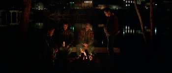 Movie still from “All the Real Girls” (2003), directed by David Gordon Green – A group of men sitting around a fire at night; Wide shot, High angle