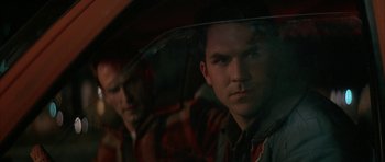 Movie still from “All the Real Girls” (2003), directed by David Gordon Green – A man holding an umbrella while standing next to another man; Close Up shot, Over the shoulder angle