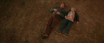 Movie still from “All the Real Girls” (2003), directed by David Gordon Green – A man and a child laying on the ground; Wide shot, Overhead angle