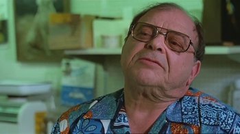Movie still from “Alligator” (1980), directed by Lewis Teague – An older man wearing glasses and a hawaiian shirt; Close Up shot, Low angle